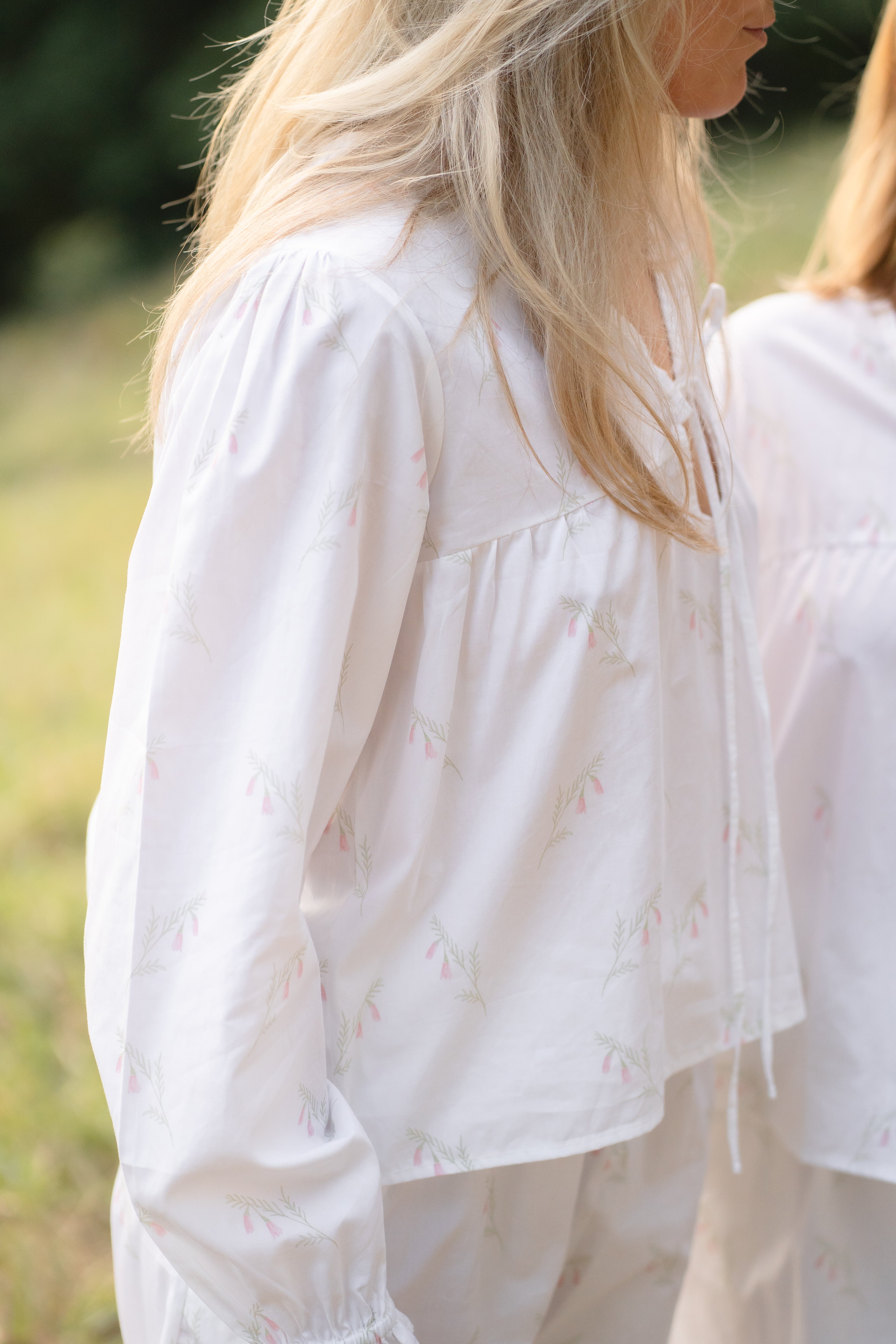 Woman wearing the Heathland Bloom cotton pyjama set by Simply Provincial, featuring delicate ruffles on the sleeves and hem of the pants. Inspired by the native Australian pink heath flower and handmade from cotton. 