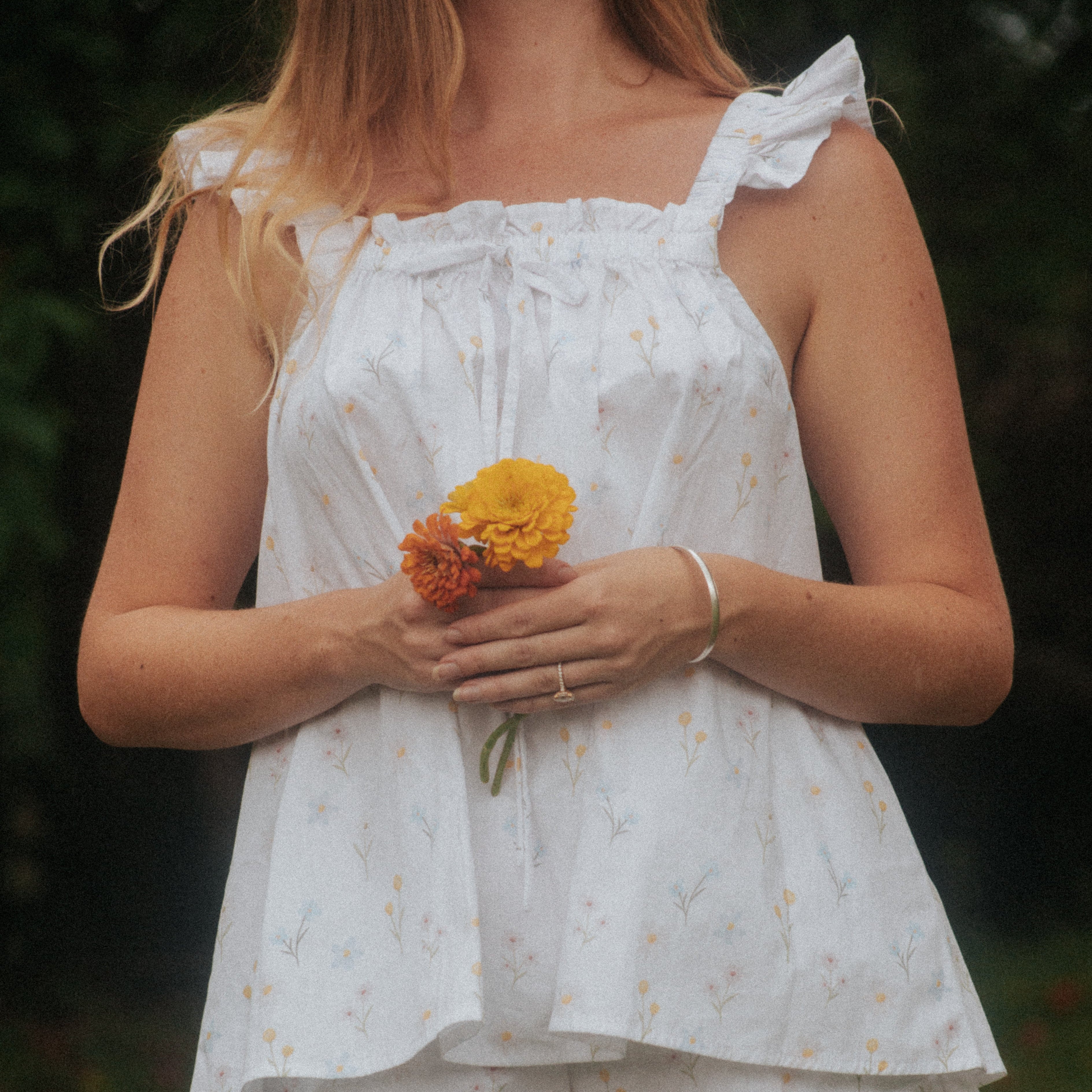 Model wearing the Wildflower Whispers cotton pyjama set with an Australian native floral print, holding flowers outdoors. 
